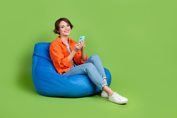 Full length photo of cute pretty woman wear jacket bean bag chatting telegram facebook empty space...