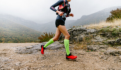 woman athlete running mountain trail in compression socks