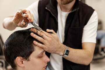Fototapeta premium hairdresser does haircut for caucasian bearded man