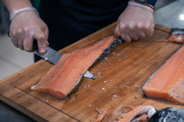 Chef preparing a salmon fish by gutting and filleting at the kitchen