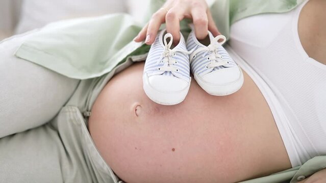 close-up belly of a pregnant woman with blue socks Pregnancy, motherhood, preparation and waiting concept.