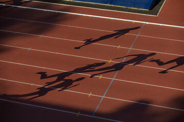 shadows woman runners run on red track stadium of sprint race