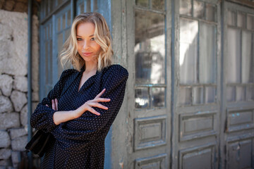 A  beautiful woman dressed in a fashion dress,  flowers in her hands  along the old town with ancient buildings of the last century