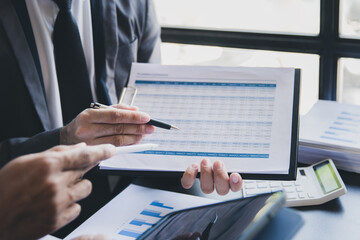 Close-up of two businessmen with pens pointing on report paper. Two Businessman discussing together in meeting room, investment projects.