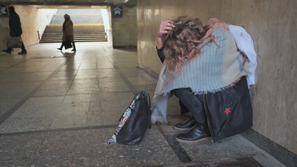 A lonely, sad girl sitting in an underpass.