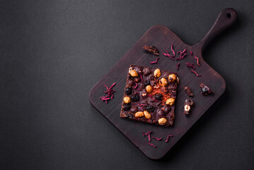 Handmade chocolate with berries, nuts and spices on a dark background