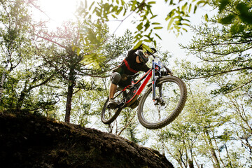 Fototapeta na wymiar downhill mountain biking rider jump hill in sunlight