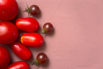 Fresh tomatoes lying layout on a table, Pink background. View from above