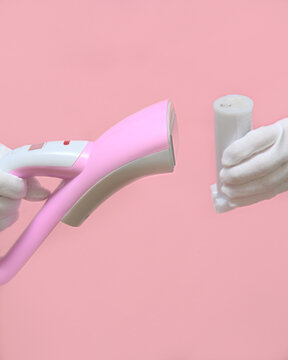 Man holding a disassembled clothes steamer with a plastic water container. pink background