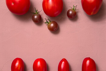 Fresh tomatoes lying layout on a table, Pink background. View from above