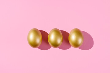 Easter template with golden eggs. Egg painted gold on pink background. Easter concept with copy space for text. Flat lay style minimalistic design.