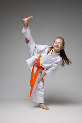 Cheerful karate training, a little girl in a kimono on a white background.
