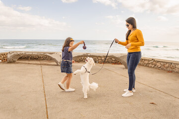 Mujer joven disfrutando de un paseo con su perro y una niña pequeña juega con el perro