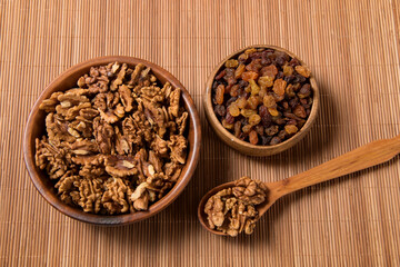 raisins and walnuts in wooden cups, wooden spoon with walnuts, top view