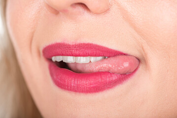 Naklejka premium Woman Face with Open Mouth And Tongue Out. Bright Red Lipstick in Use and White Teeth.