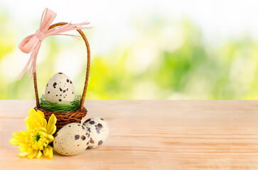 Easter background with a basket and quail eggs on a wooden table.