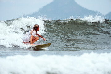 back view mid adult caucasian woman surfing the waves in Brazil