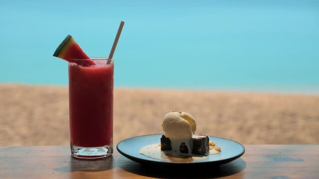 Watermelon refreshment drink and cake with ice cream, blue sea on background