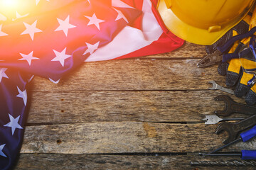 Flag America and construction tool on wooden background are illuminated by sunlight.Concept Labor Day first May.