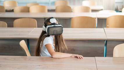 Caucasian schoolgirl wearing virtual reality glasses in the classroom. 