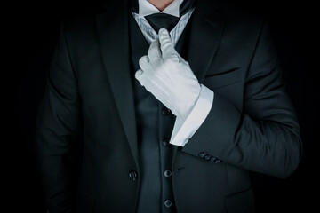 Isolated Close-Up of Butler or Concierge in Dark Suit and White Gloves Straightening Tie. Service Industry and Professional Hospitality.