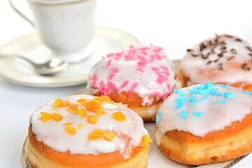 Preparing many types of donuts for traditional party Fat Thursday or Shrove Tuesday - close-up of various sweet pastries on plate with cup of coffee