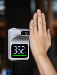 People measure temperature with left hand on sensor before getting into the building, restaurant and hotel. Flu, cold, fever, covid19 prevention and protection concept. Automatic infrared thermometer.
