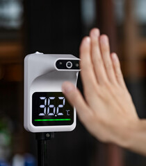 People measure temperature with right hand on sensor before getting into the building, restaurant and hotel. Flu, cold, fever, covid19 prevention and protection concept. Automatic infrared thermometer
