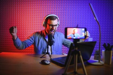 A video blogger records content in his studio. The host of the video blog is a young man who is...