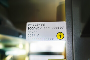 Information plate with Braille alphabet for person with blindness on the train door. Assistance and care for people with poor vision.
