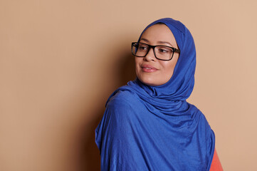 Attractive confident Middle-Eastern Muslim woman in blue hijab, squinting looking to the side...