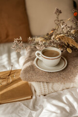 Hot mug of cappuccino on wooden tray on the bed, breakfast, bouquet of dried flowers. Spring scenery. Cozy house. Beige natural colors.