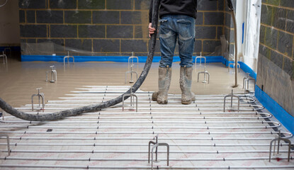 Screed floor being poured over under floor heating pipes.