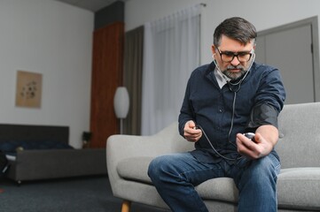 Senior man using medical device to measure blood pressure