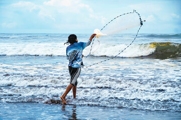 Fisherman casting net on tropical beach