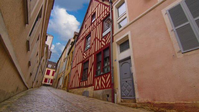 View of a beautiful street with old traditional French houses in the center of Auxerre with clouds in the background. Legacy of French history. Historic hotels, colorful houses in France. Time Lapse