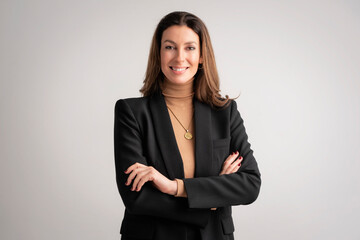 Confident mid aged woman wearing black blazer and standing at isolated background