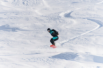 Fototapeta na wymiar Freerider on snowboard skillfully ride down and jump at deep fresh snow in Gudauri Georgia