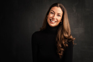 Headshot of an attractive middle aged woman with toothy smile wearing turtleneck sweater while...