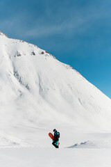 Naklejka na ściany i meble great view of man freerider with snowboard walks against winter mountain landscape