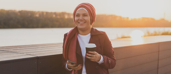 Banner Asian muslim woman wearing hijab scrolling social networks having coffee break outdoor on...