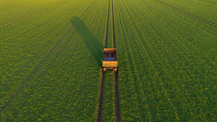 Hänger von einem Traktor steht auf einem grünen Feld mit Spuren, Symmetrisch von oben im...