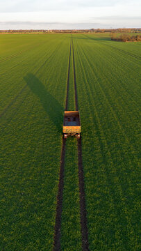 Hänger von einem Traktor steht auf einem grünen Feld mit Spuren, Symmetrisch von oben hochkant