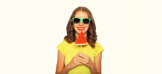 Summer portrait of happy smiling young woman with lollipop or ice cream shaped slice of watermelon wearing sunglasses on white background
