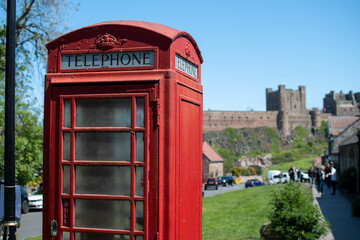 Close up of a traditional red UK telephone box in the village green at Bamburgh, UK
