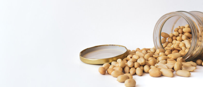 Roasted peanuts pouring from jar closeup. High resolution photo image can be used as large printed canvas, website banner, social media post. Blank copy space for advertising texts.