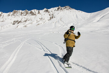 Fototapeta na wymiar snowboarder riding freeride on snow down the slope against the backdrop of the mountains