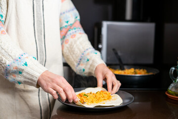 Girl cooking. Girl closing the tortilla to make a vegetable rice burrito. Mushrooms, green and red peppers and onion