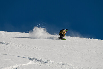 Naklejka na ściany i meble snowboarder skilfully descends down a snowy mountain slope