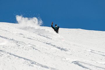 Naklejka na ściany i meble sportive man snowboarder skilfully descends down a snowy mountain slope